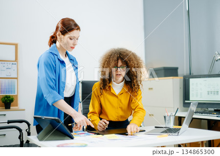 Women designers working on mobile app UX UI with color palettes, wireframes, and sticky notes. Teamwork, prototyping, and layout planning 134865300