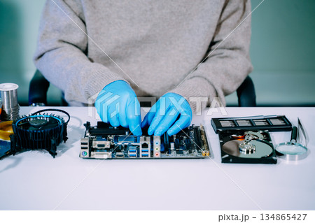 Closeup of expert soldering a green PCB board using precision tools. Ideal for electronics, circuit repair, engineering, tech Closeup of expert soldering a green PCB board using precision tools. Ideal for electronics, circuit repair, engineering, tech 134865427