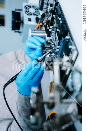 Closeup of technician soldering a computer motherboard with precision tools, showcasing electronics repair, hardware maintenance, and modern technology Closeup of technician soldering a computer motherboard with precision tools, showcasing electronics repair, hardware maintenance, and modern technology 134865493