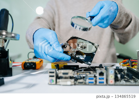 Hard disk drive on the technician's desk and a computer motherboard as a component. the concept of data, hardware 134865519