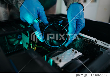 Closeup of technician in gloves holding CPU cooler and heat gun over desktop PC. Ideal image for computer repair, cooling system, and hardware Closeup of technician in gloves holding CPU cooler and heat gun over desktop PC. Ideal image for computer repair, cooling system, and hardware 134865555