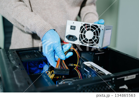 Computer technician in gloves safely repairing desktop hardware. Close-up view of hands fixing GPU and motherboard inside open PC case. Perfect for tech and repair concepts. Computer technician in gloves safely repairing desktop hardware. Close-up view of hands fixing GPU and motherboard inside open PC case. Perfect for tech and repair concepts. 134865563