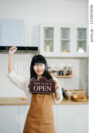 Young Asian woman coffee shop owner holding notepad and digital tablet ready to receive orders in cafe restaurant. Young Asian woman coffee shop owner holding notepad and digital tablet ready to receive orders in cafe restaurant. 134865696