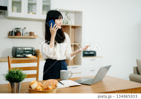 Woman using laptop while sitting at home. Young woman sitting in kitchen Woman using laptop while sitting at home. Young woman sitting in kitchen 134865833