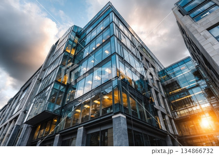 Modern Glass Office Building Reflecting City Skyline Under Dramatic Cloudy Sky Modern Glass Office Building Reflecting City Skyline Under Dramatic Cloudy Sky 134866732