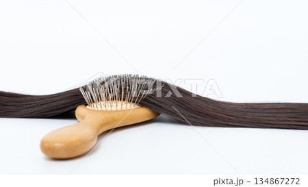 Wooden hairbrush resting on smooth, straight brown hair against a clean white background, showcasing hair care and grooming essentials Wooden hairbrush resting on smooth, straight brown hair against a clean white background, showcasing hair care and grooming essentials 134867272