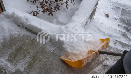 Snow shovel is clearing thick snow from a concrete pathway during a snowstorm, showcasing winter weather challenges and outdoor maintenance efforts Snow shovel is clearing thick snow from a concrete pathway during a snowstorm, showcasing winter weather challenges and outdoor maintenance efforts 134867292