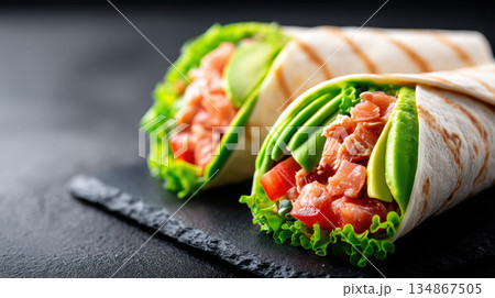 Fresh and vibrant plant based wraps filled with salmon, lettuce, tomatoes, and avocado showcase delicious approach to longevity and healthy eating. Enjoy this nutritious meal option 134867505