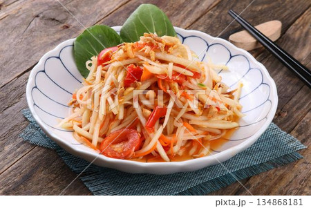 A vibrant and appetizing plate of Thai som tam salad on a rustic wooden table A vibrant and appetizing plate of Thai som tam salad on a rustic wooden table 134868181