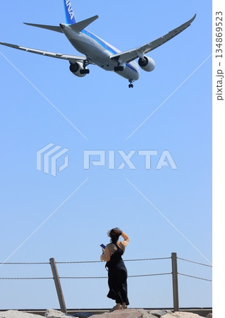 飛行機を見上げる女性 羽田空港の着陸コース 飛行機を見上げる女性 羽田空港の着陸コース 134869523