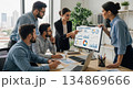 Business team analyzing data on screen in modern office setting 134869666
