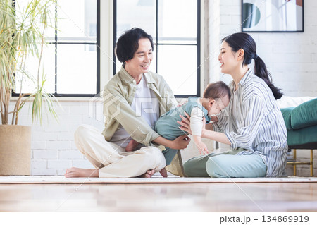 リビングで赤ちゃんを抱く夫婦 リビングで赤ちゃんを抱く夫婦 134869919