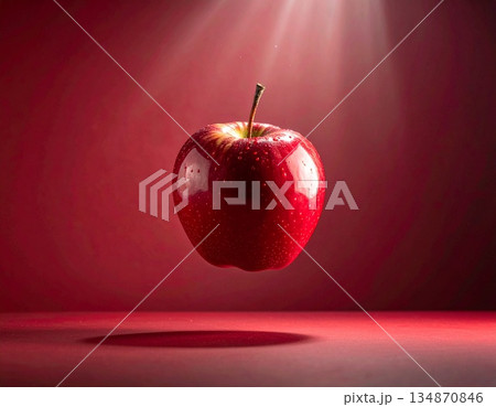赤い背景のスポットライトに照らされ宙に浮かぶ赤いリンゴ 134870846