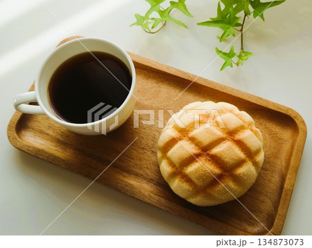 白いマグカップに入ったホットコーヒーとメロンパン 134873073