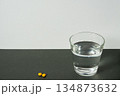 水のグラスと黄色い錠剤（シンプル背景） 134873632