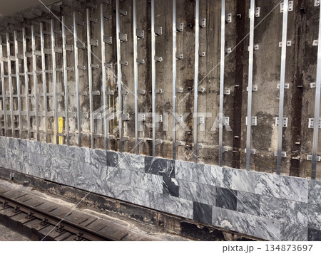 New steel frame with partially installed tiles on wall. Concrete main wall with new frame and tiles in process of being finished. Tiled wall being erected. New tiles during wall renovation 134873697