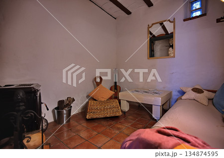 Cozy rustic living room with wicker chair guitar table and sofa in warm homey setting Cozy rustic living room with wicker chair guitar table and sofa in warm homey setting 134874595
