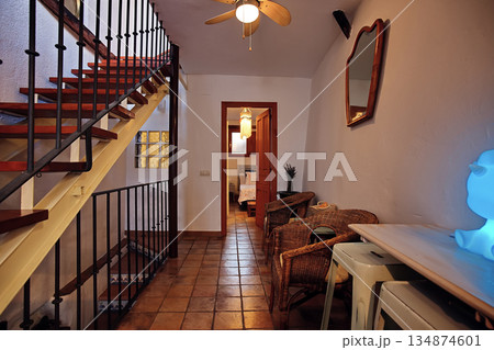 Cozy rustic hallway interior with wooden stairs, wicker chairs, and a blue glow lamp in a warm home setting Cozy rustic hallway interior with wooden stairs, wicker chairs, and a blue glow lamp in a warm home setting 134874601