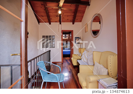 Cozy hallway living area with yellow armchairs, blue chair, and wooden beams leading to a bedroom Cozy hallway living area with yellow armchairs, blue chair, and wooden beams leading to a bedroom 134874613