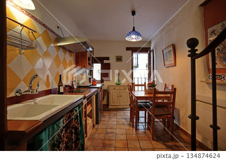 Cozy rustic kitchen and dining area with yellow tile backsplash and wooden table 134874624