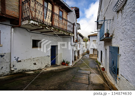Cozy white village alley with blue doors and potted plants along a stone street in town 134874630