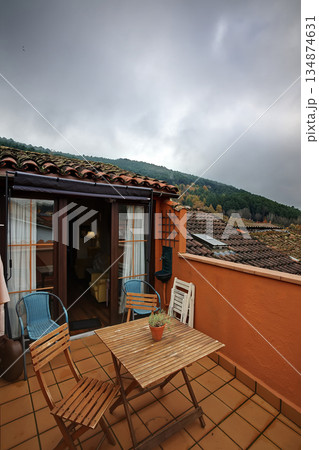 Cozy terrace dining area on an orange balcony overlooking misty hills and cloudy sky outside Cozy terrace dining area on an orange balcony overlooking misty hills and cloudy sky outside 134874631