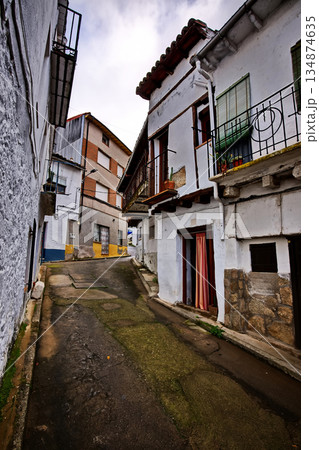 Charming narrow street with whitewashed houses, balconies, and worn pavement in a quaint village alleyway Charming narrow street with whitewashed houses, balconies, and worn pavement in a quaint village alleyway 134874635