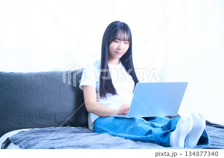 ベッドの上でリラックスしてパソコンを操作する若い女性 ベッドの上でリラックスしてパソコンを操作する若い女性 134877340