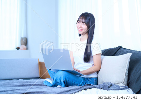 ベッドの上でリラックスしてパソコンを操作する若い女性 134877343