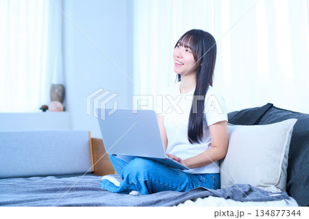 ベッドの上でリラックスしてパソコンを操作する若い女性 ベッドの上でリラックスしてパソコンを操作する若い女性 134877344