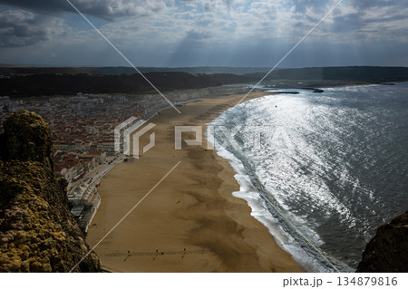 Aerial view of a coastal town and long sandy beach under sunlit ocean light 134879816