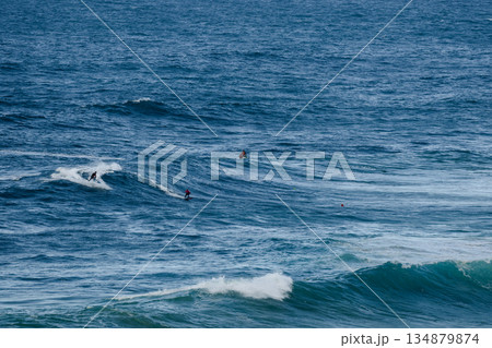 Surfers ride powerful blue waves in the ocean, capturing dynamic coastal sport action Surfers ride powerful blue waves in the ocean, capturing dynamic coastal sport action 134879874