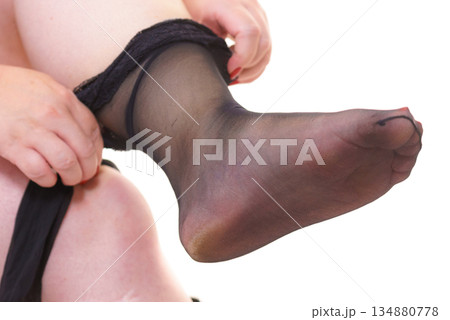 Woman plus size puts on black nylon stockings 134880778