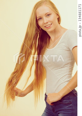 Blonde girl brushing her long hair Blonde girl brushing her long hair 134881171