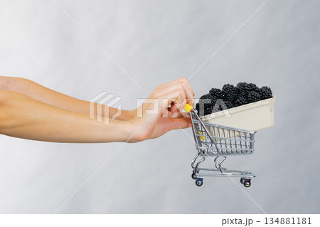 Hand holds blackberry fruits in shopping cart 134881181