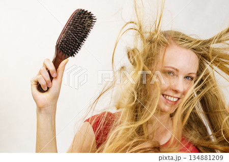 Blonde girl long blowing hair holds natural bristles brush Blonde girl long blowing hair holds natural bristles brush 134881209