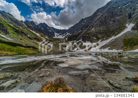 Panoramic view of a frozen glacial lake surrounded by snowy peaks in High Tatras 134881341