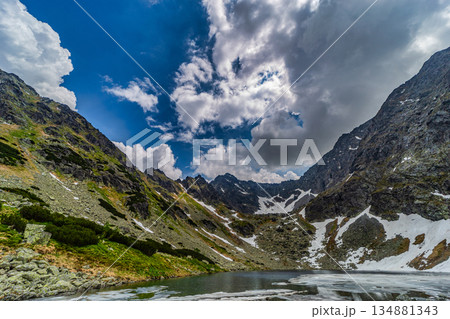 Panoramic view of a frozen glacial lake surrounded by snowy peaks in High Tatras Panoramic view of a frozen glacial lake surrounded by snowy peaks in High Tatras 134881343