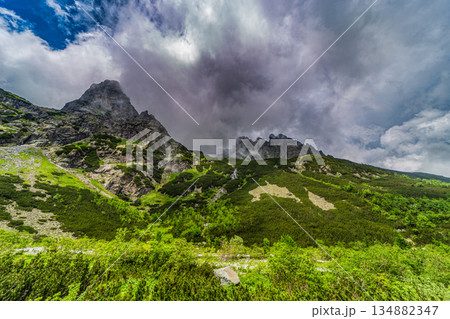 Traditional mountain hut by a lake under a dramatic stormy sky Traditional mountain hut by a lake under a dramatic stormy sky 134882347