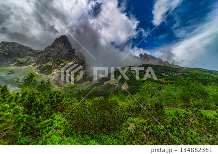 Traditional mountain hut by a lake under a dramatic stormy sky 134882361