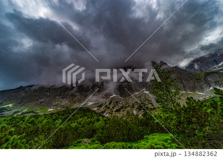 Dramatic storm clouds and mist covering mountain peaks 134882362