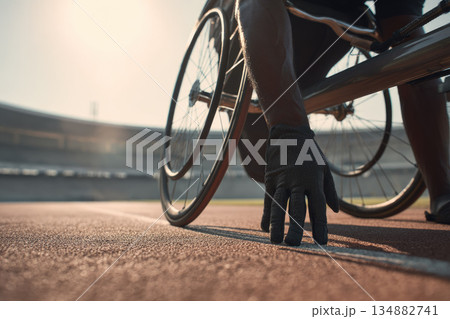 Disabled athlete training on outdoor track with determination and support, preparing for race in wheelchair under sunlight at stadium 134882741