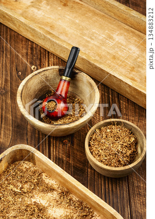 Smoking pipe with tobacco on a table. Smoking pipe with tobacco on a table. 134883212
