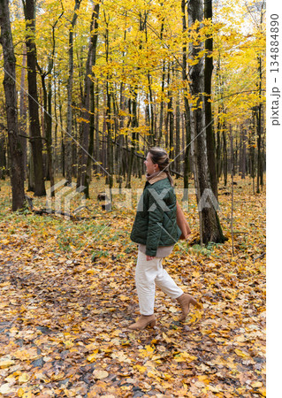 Woman walks through yellow autumn leaves among tall trees in Timiryazevsky Park, Moscow, calm natural colors and relaxed mood Woman walks through yellow autumn leaves among tall trees in Timiryazevsky Park, Moscow, calm natural colors and relaxed mood 134884890