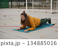 A woman stands in a plank position on a yoga mat 134885016