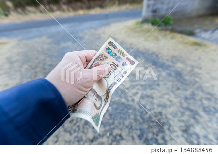 左手で握りしめている一万円札　しわくちゃになっているお札 134888456