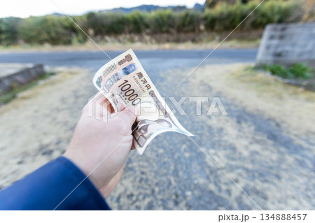 左手で握りしめている一万円札　しわくちゃになっているお札 134888457