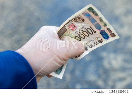 左手で握りしめている一万円札 しわくちゃになっているお札 左手で握りしめている一万円札 しわくちゃになっているお札 134888461