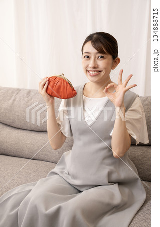 ソファーに座って赤い財布を持つ妊娠8ヶ月の女性 134888715