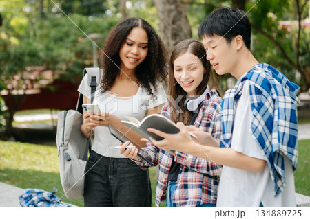 Two smart young Asian college students focusing on his school project, looking at laptop and tablet, discussing and working together Two smart young Asian college students focusing on his school project, looking at laptop and tablet, discussing and working together 134889725